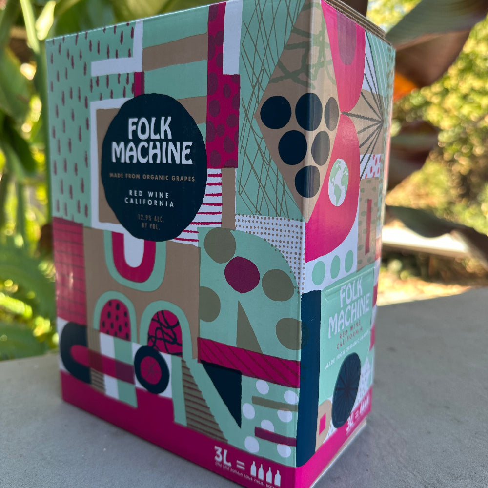 Colorful geometric-patterned box with 'Folk Machine' branding against a natural background
